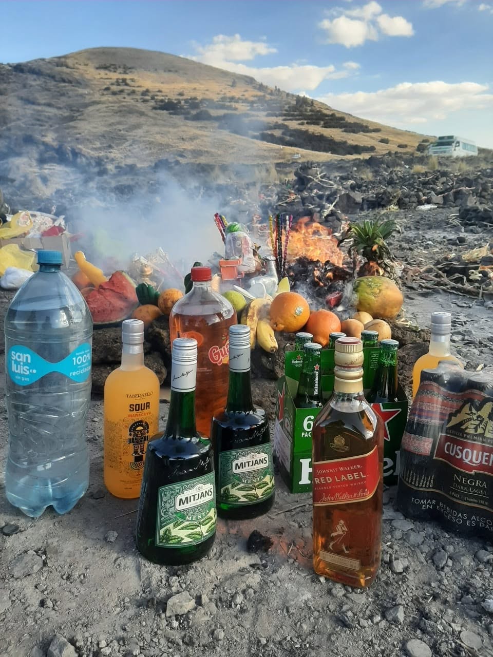 Ofrenda ritual con fuego y botellas en los Andes